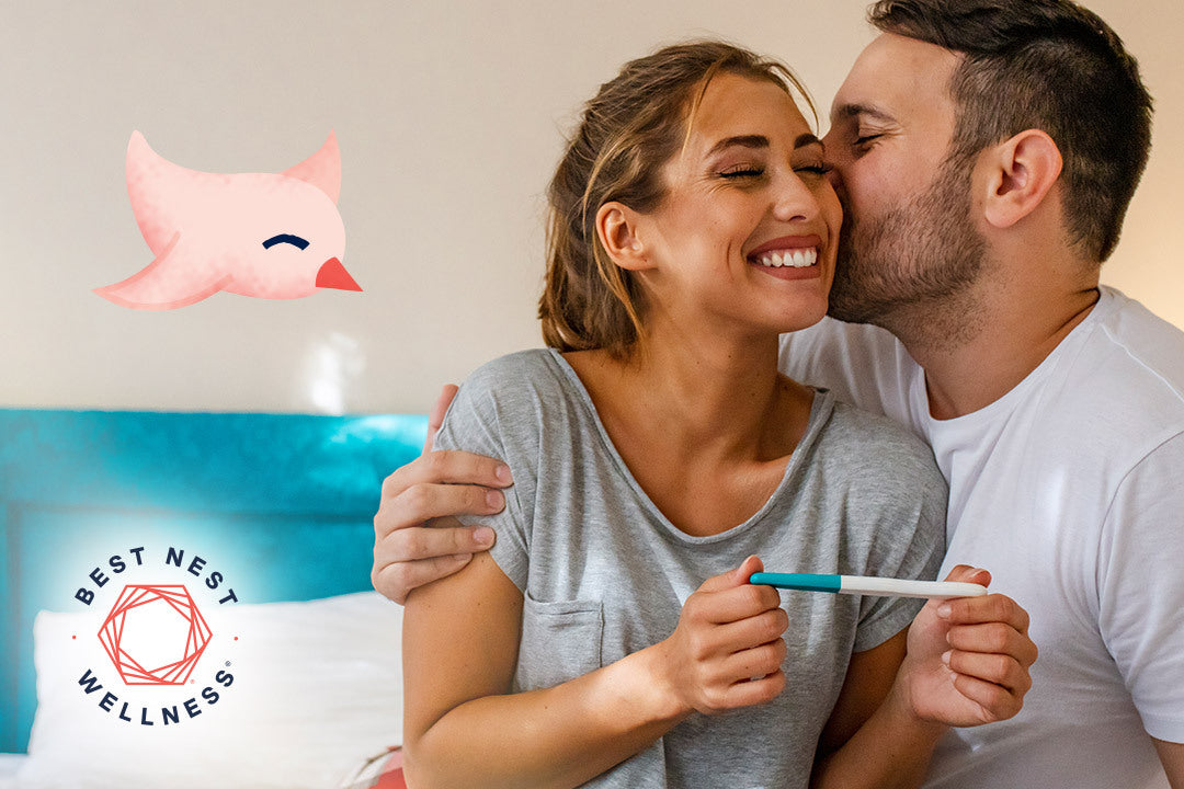 A man kissing a smiling woman on the cheek, both standing indoors.