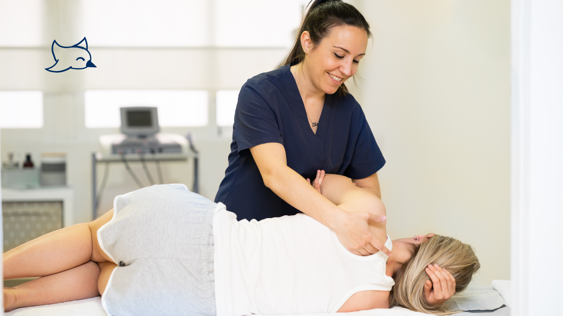 A woman in a blue shirt massages another woman's back on a bed in a room, focusing on the act of massage.