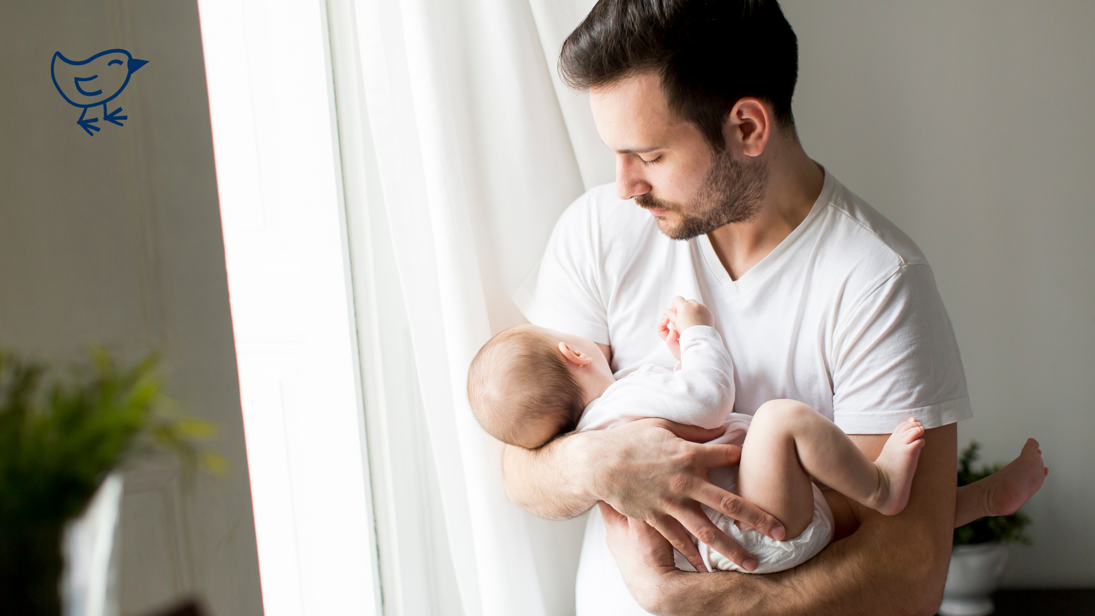 A man holding a baby indoors, both facing the camera.