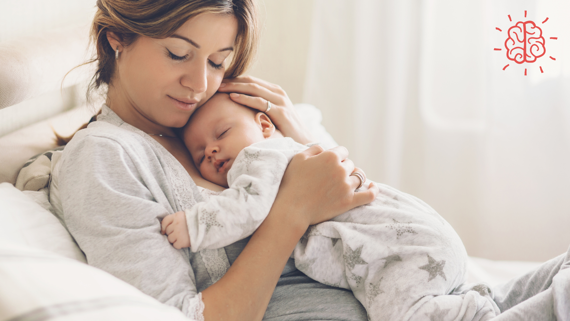 A woman holding a sleeping baby indoors, both appear comfortable and relaxed.