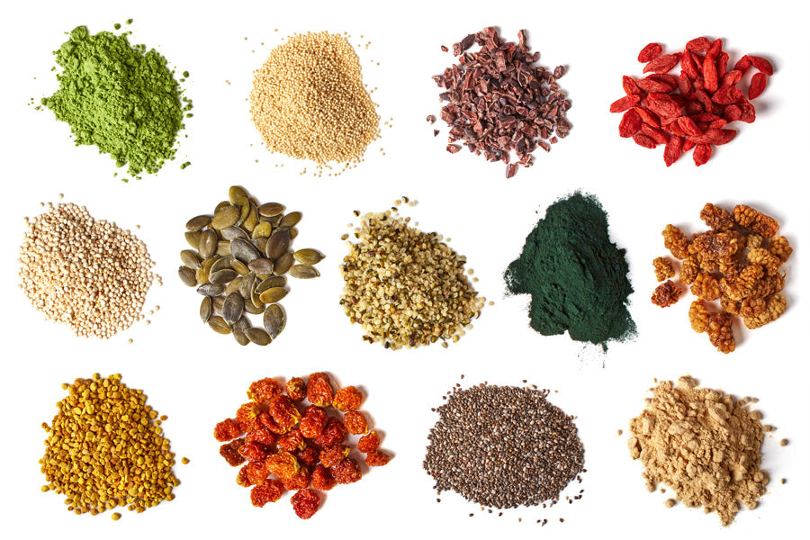 A collection of various food piles including green powder, brown and white pebbles, yellow pebbles, and different grains on a white background.